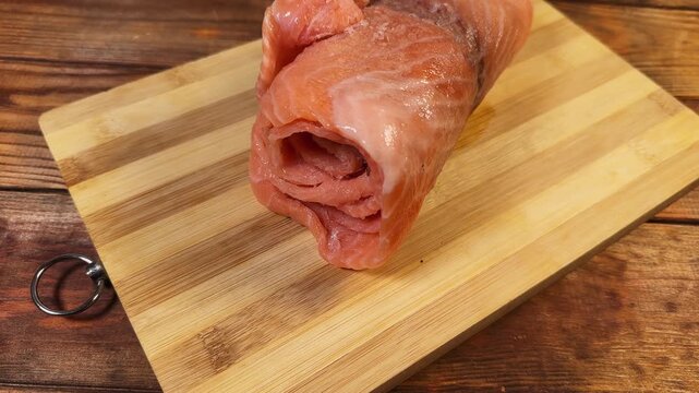 Raw frozen slice of salmon rolled up on cutting board