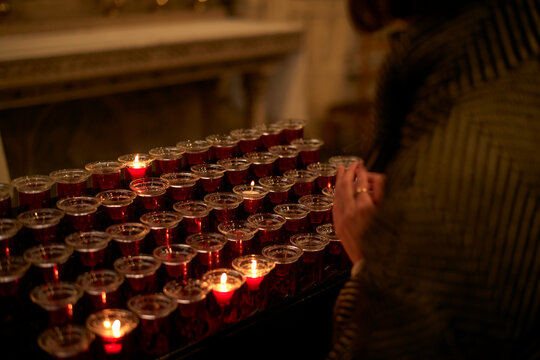 Person lighting candles in a dimly lit room with a reflective surface nearby. Zurich, Switzerland