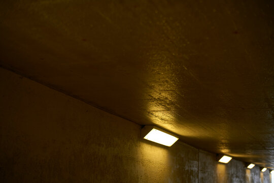 Dimly lit concrete tunnel with a series of rectangular lights on the ceiling. Brussels, Belgium
