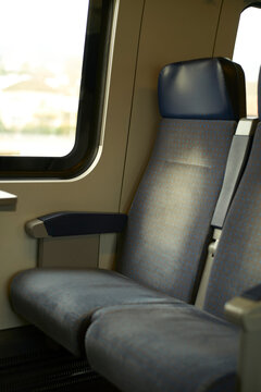 Empty train seat by a window with soft light filtering through creating a serene atmosphere. Brussels, Belgium