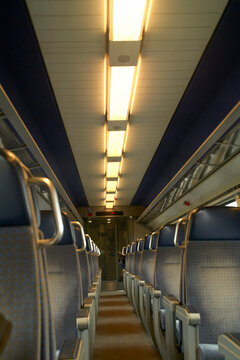 Interior view of an empty train carriage with blue seats and overhead lighting. Brussels, Belgium
