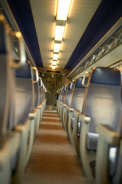 Empty train carriage with rows of blue seats and overhead lighting, creating a quiet ambiance. Brussels, Belgium