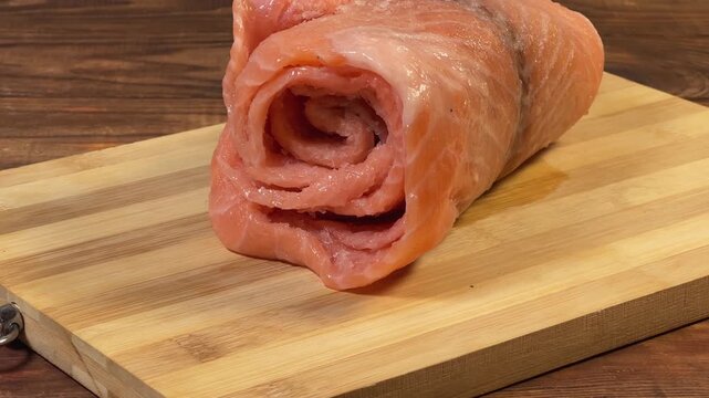 Raw frozen slice of salmon rolled up on cutting board