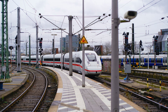 Modern high-speed train arriving at a busy urban railway station on a cloudy day. Cologne, Germany