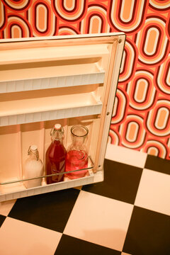 Vintage fridge door with bottles and retro pattern of orange and white geometric wallpaper. Brussels, Belgium