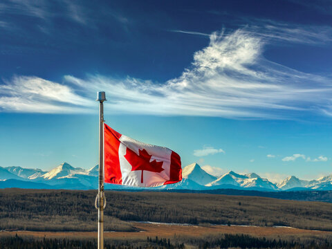Canadian flag waving with mountains and clear sky in the background. Close to Calgary, Canada