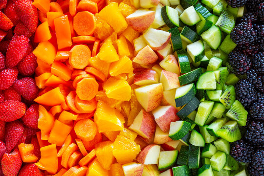 Colorful array of fresh fruits and vegetables arranged in a rainbow gradient.
