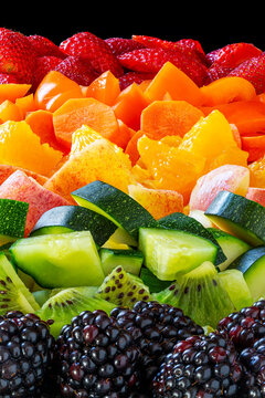 Colorful arrangement of various sliced fruits and vegetables in a rainbow pattern.