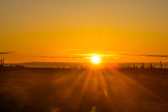 Sunset over a desert landscape with sun rays casting warm golden hues across the sands. Kenai Peninsula, Alaska, USA