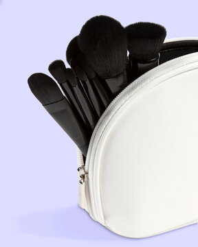 A white makeup bag filled with black brushes on a light purple background.