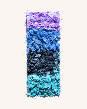 Crushed pastel eyeshadow in purple, blue, and turquoise shades on a white background.