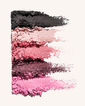Various shades of pink and black makeup powders streaked on a light background.