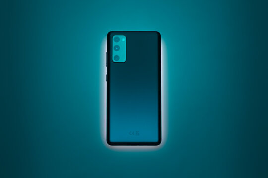 Smartphone with glowing teal gradient back and dual camera setup on dark background.