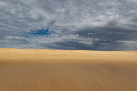 Desert landscape with a dramatic cloudy sky and flat horizon. Playa La Cachora, Todos Santos, Mexico