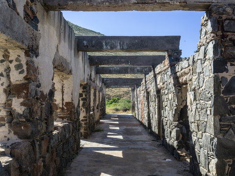 Ruins of a stone building with open roof beams and a distant view of a sunny landscape. La Paz, Mexico