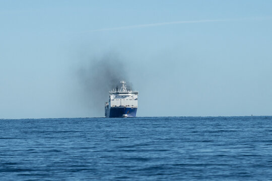 Large ferry ship emitting smoke sails across a calm blue ocean under a clear sky. Canada