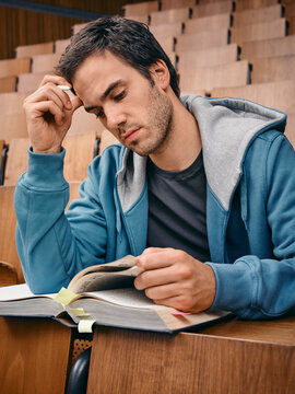 Young man in a blue hoodie studying in an empty lecture hall. Germany