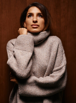 Woman in a cozy sweater against a wooden background gazing upwards contemplatively Germany