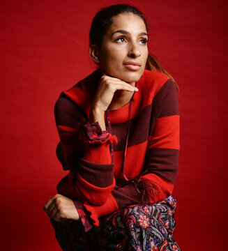 Woman in red and brown striped sweater posing against a matching red background. Germany