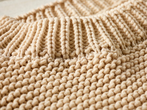 Close-up of beige knitted fabric with intricate patterns and texture. Germany