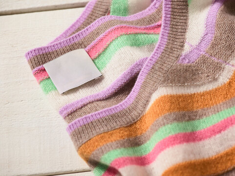 Colorful striped woolen fabric with blank white label on a wooden surface. Germany
