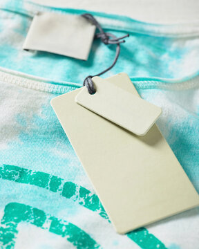 Turquoise tie-dye shirt with blank paper tags attached close-up. Germany