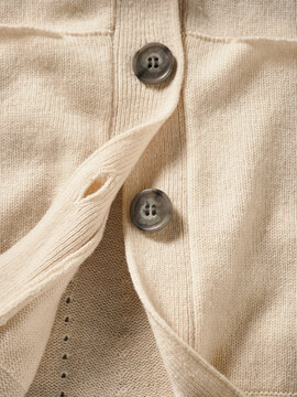 Close-up of a beige wool sweater with two grey buttons. Germany
