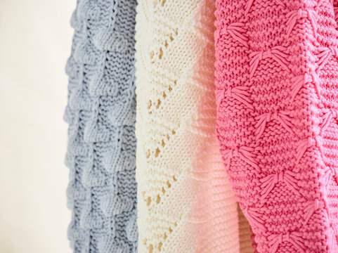 Blue, white, and pink textured knitted fabrics hanging side by side showcase intricate patterns. Germany