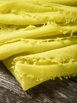 Yellow textured fabric with frayed edges on rustic wooden surface. Germany