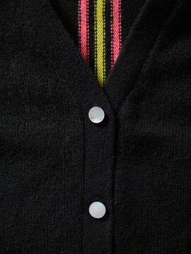Black cardigan with colorful striped detail and white buttons in a close-up view. Germany