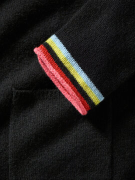 Black fabric with a colorful striped cuff draped over a pocket. Germany