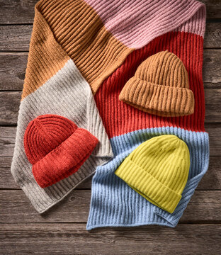 Colorful knitted hats and scarves arranged on a rustic wooden surface. Germany