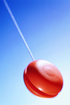 Red yo-yo with string against a bright blue sky background Germany