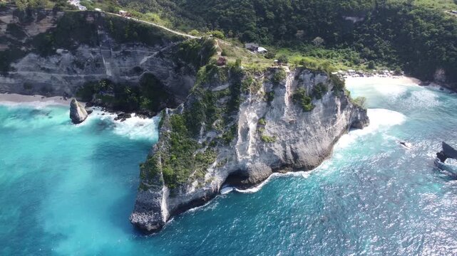 Aerial drone orbiting left from Diamond Beach cliff lookout revealing Atuh Beach cove in Nusa Penida, Bali, Indonesia.