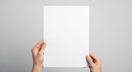 Fototapeta premium Man holding empty white sheet of paper. Blank flyer for design presentation. Mockup of cardboard card for message or branding. Office stationery for document template on grey background.
