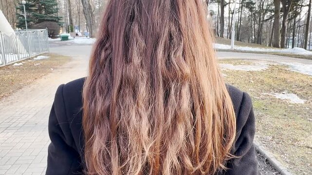 Close-up of long brown hair from the back, natural texture of women's hairstyle with soft waves