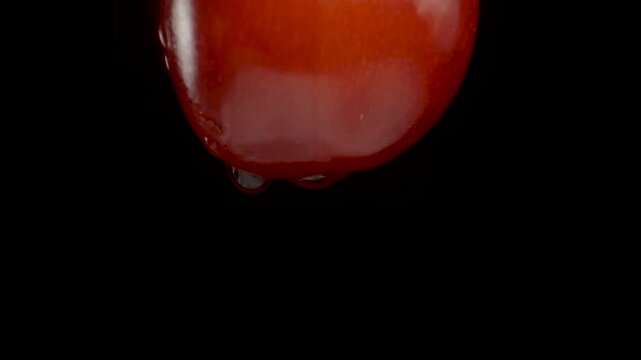 A single ripe cherry berry on a black background. Isolated. Dolly slider extreme close-up.