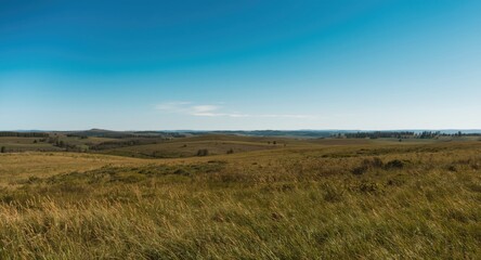Fototapeta premium A vast green landscape extending under an open blue sky