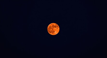 Naklejka premium Magnified close up view of a scarlet full moon brightly shining in a pristine night sky using telephoto lens