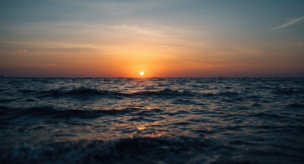 Obraz premium Scenic evening seascape featuring colorful sun setting above tranquil sea waves