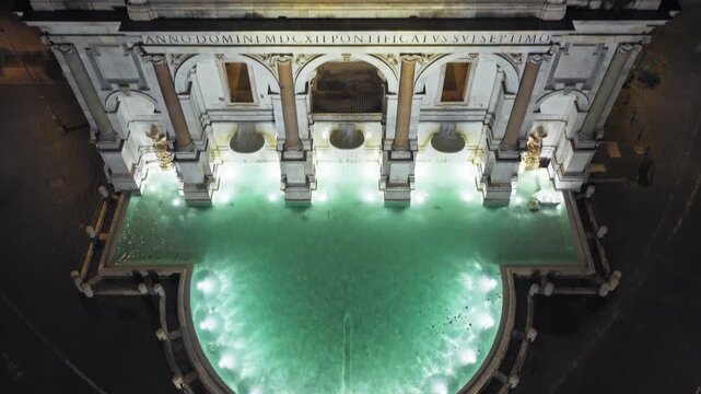 Top-down aerial drone flight from the glowing basin over the lit facade and coat of arms of Fontana dell'Acqua Paola at night, Rome, Italy, Europe