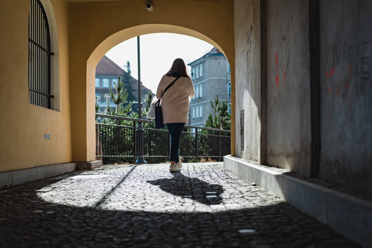 woman seen from behind, stepping out of the underpass into the sunlight