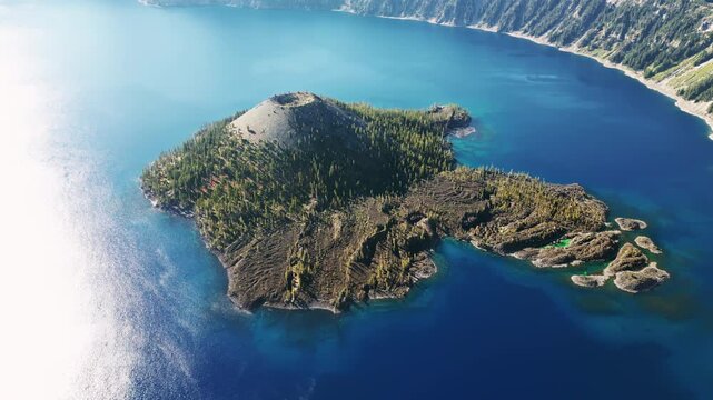 Aerial drone view of Wizard Island volcano cone rising from the deep blue waters of Crater Lake National Park, Oregon