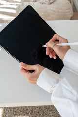 Female hands holding a digital tablet with one hand and drawing with a stylus in the other, technology and digital creativity concept on white background © Juli
