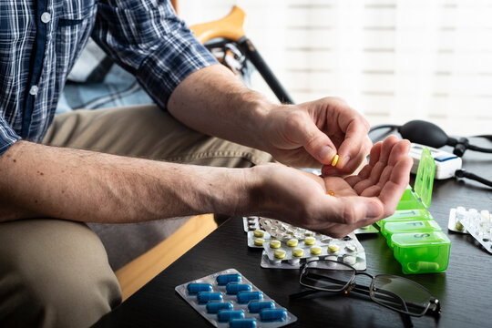 Middle aged caucasian man counts out pills for distributing scheduled dose of medication into pillbox