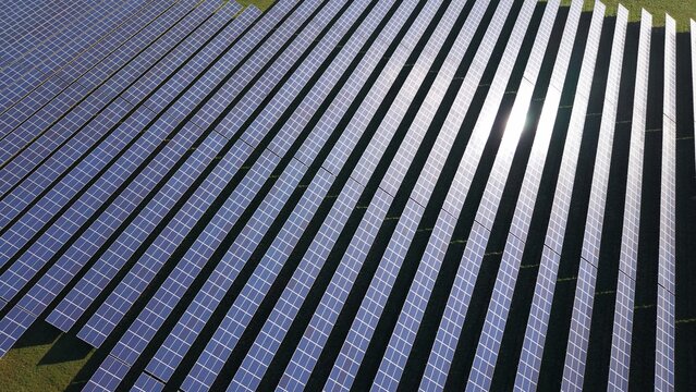 Aerial view of rows of solar panels stretching across the landscape, reflecting the sunlight, creating a shimmering effect, Retford, United Kingdom.