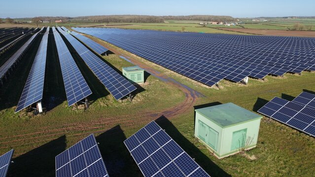 Aerial view of a vast solar farm stretching towards the horizon under a clear sky, promising a sustainable future, Retford, United Kingdom.