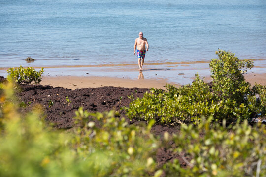 A male middle aged open water swimmer standing in the water at Suttons Beach, Redcliffe
