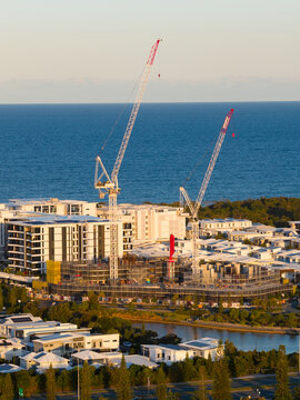 Aerial view of  tall cranes on a construction site on top of highrise buildings near the coast