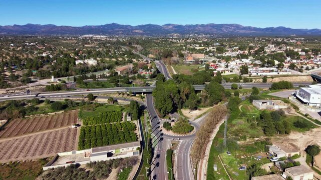 Aerial view of multilane road junction with overpass, roundabout and feeder roads, showing lane geometry, traffic flow and integration with suburban and agricultural areas in Lliria, Spain
